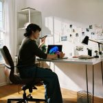 Person working at desk with laptop and phone.